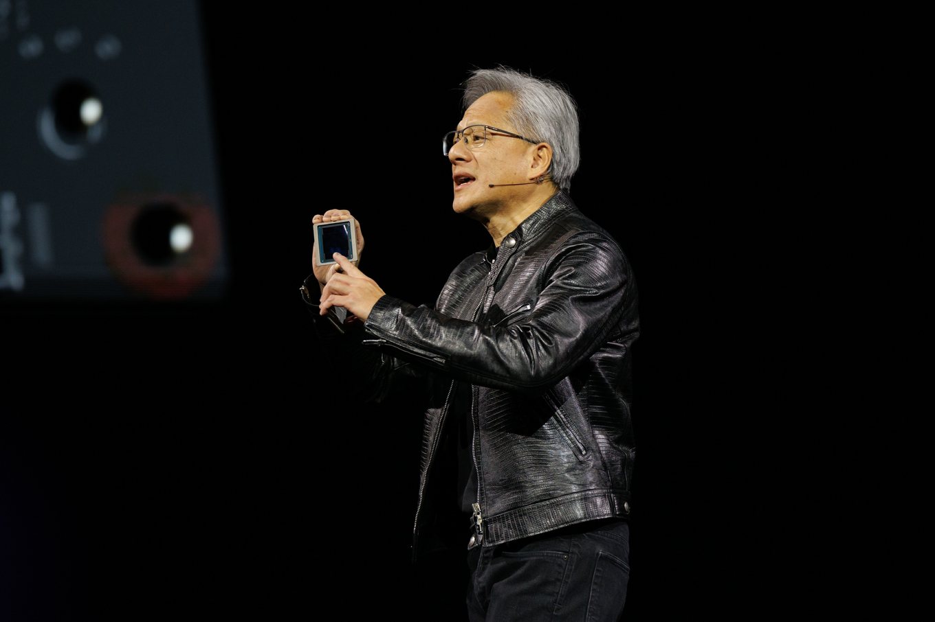 Jensen Huang holds up a Blackwell chip on stage at NVIDIA GTC 2024